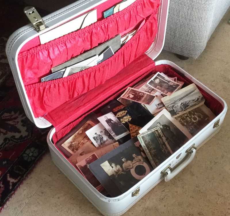 A photo of an open suitcase with a red lining filled with old photographs