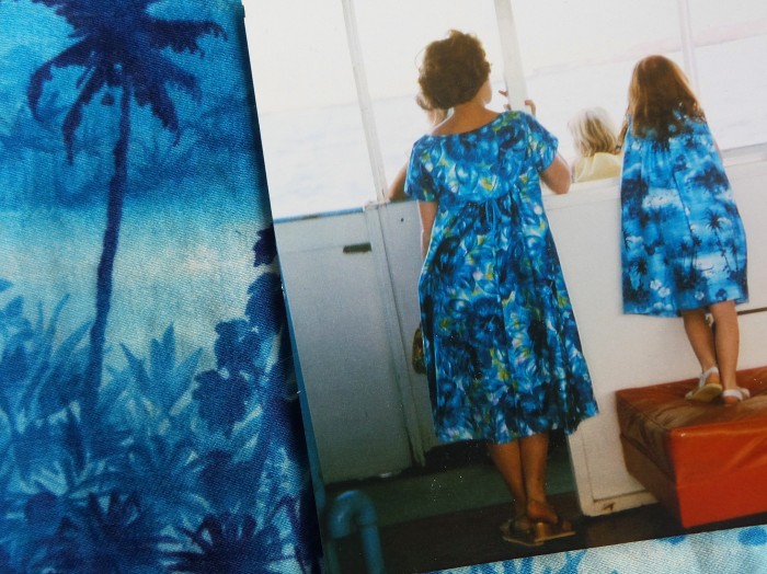 A mother and daughter in matching Hawaiian-print dresses, on a boat, taken from behind