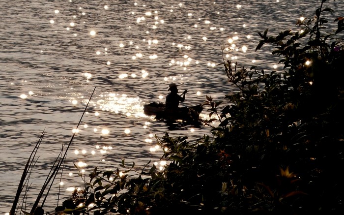 A photo of a fisherman in a boat at sunset, Lake Atitlan, Guatemala